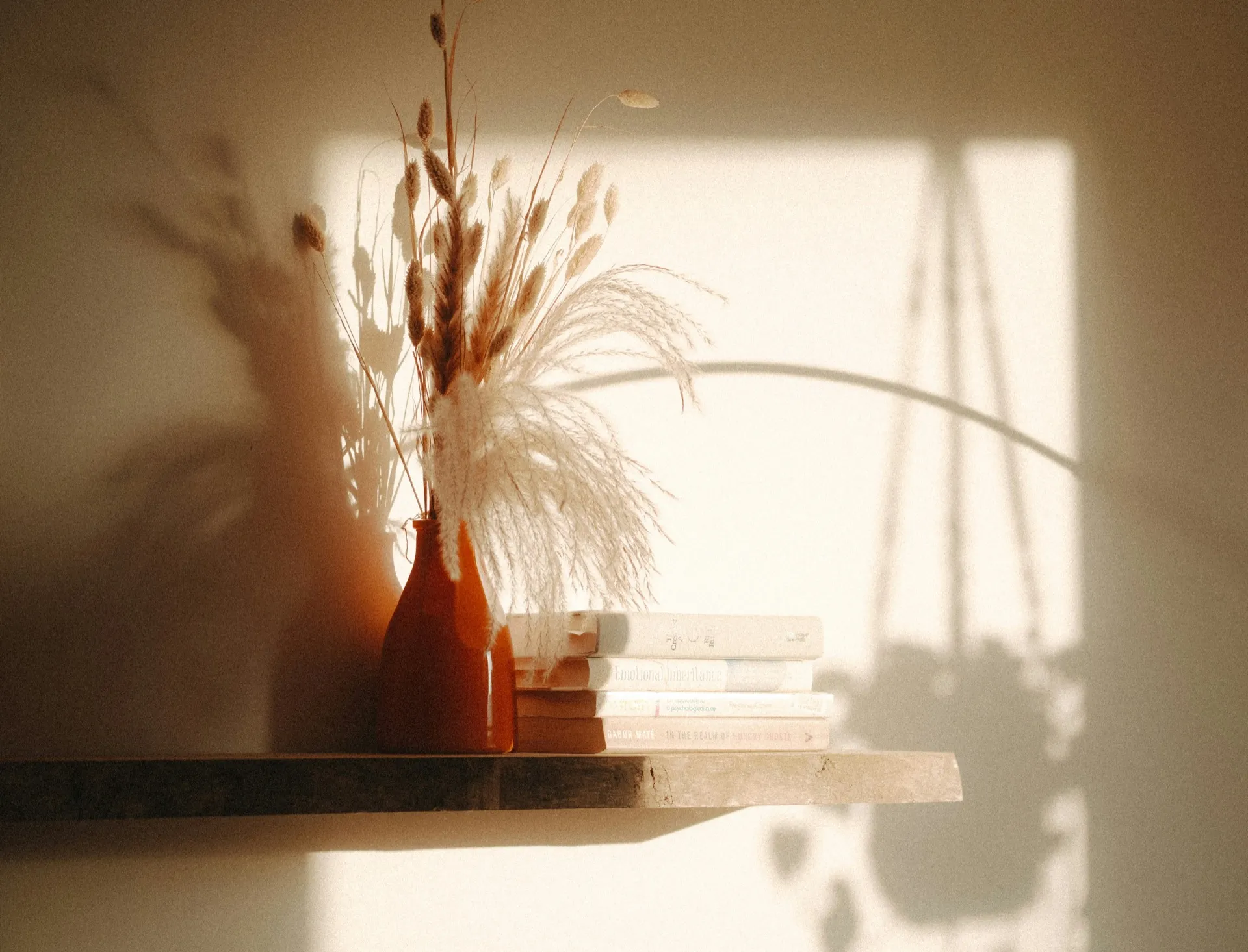 Stapel boeken en een vaas met bloemen in warm ochtendlicht